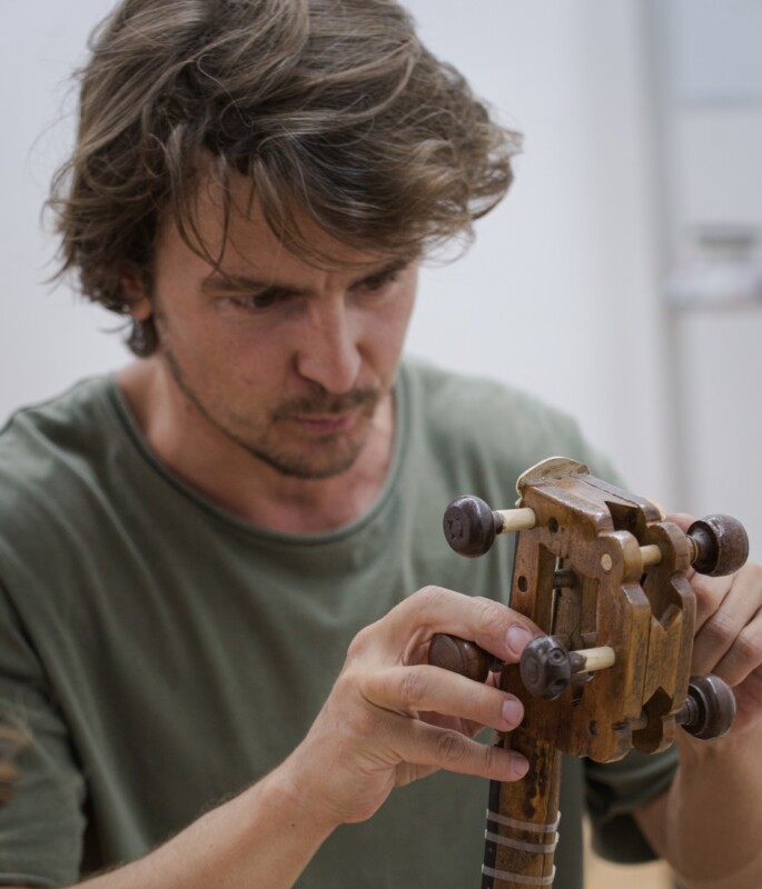 Музыкант настраивает этнический струнный инструмент